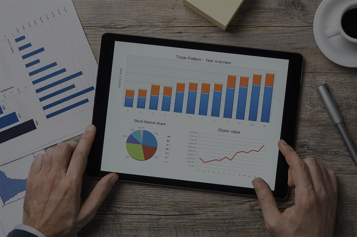 Top view of digital tablet with financial year overview on screen. Businessman analyzing investment charts with digital tablet on wooden desk at office. positive stock market trend.
